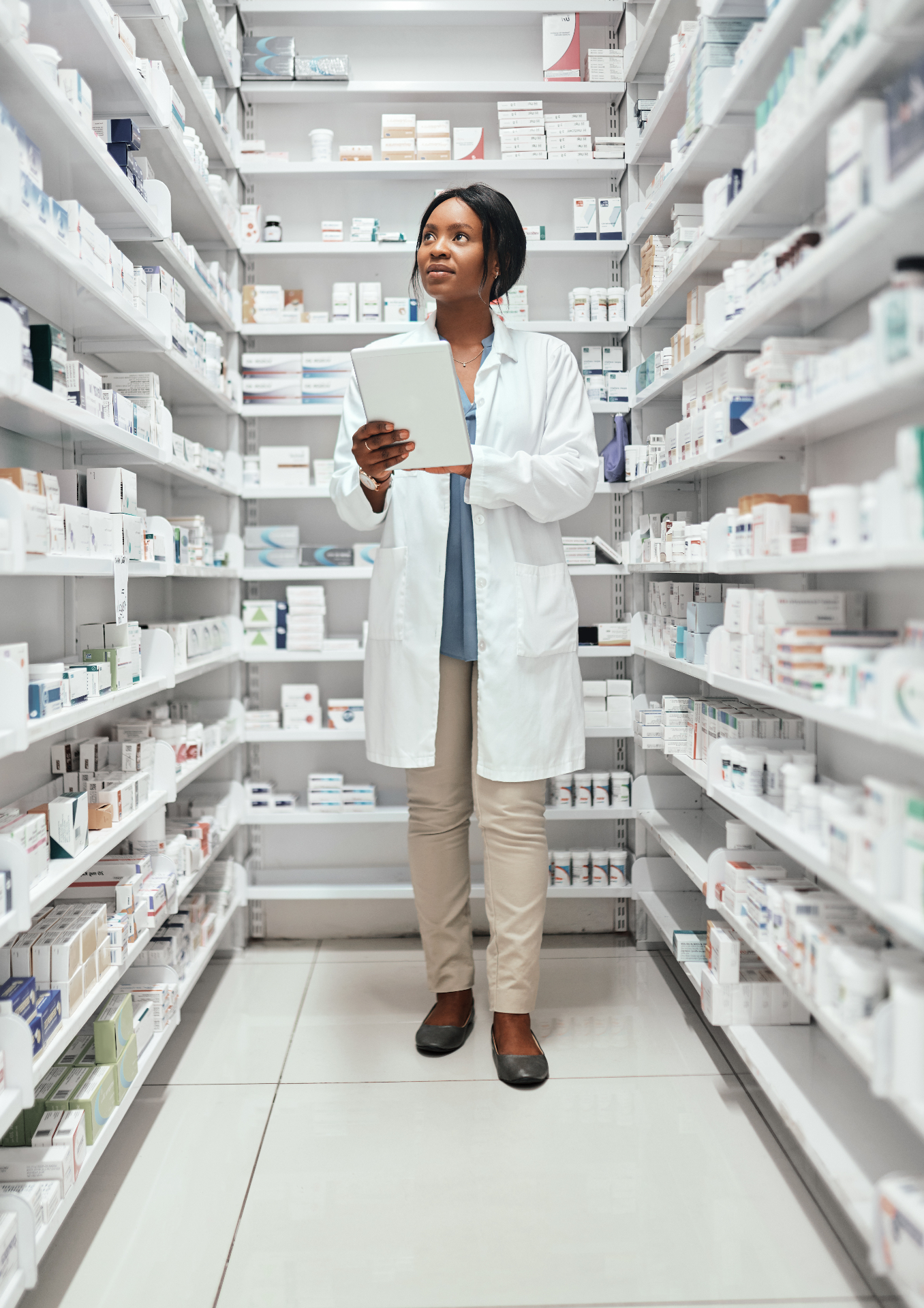 Pharmacist reviewing inventory in pharmacy aisle